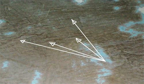 Photo: Closeup of the ply outer skin, with arrows pointing to cracks in the ply.